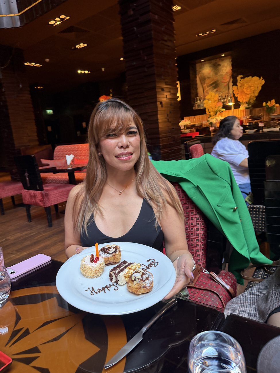 MJ delighted at the Chef&rsquo;s Table, holding a plate of four desserts with Happy Birthday written in chocolate, shared to her anniversary group chat